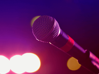 Close-up of a microphone against a colorful, blurred background of stage lights